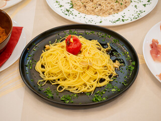 Delicious spaghetti with garlic, oil and chili pepper decorating restaurant table