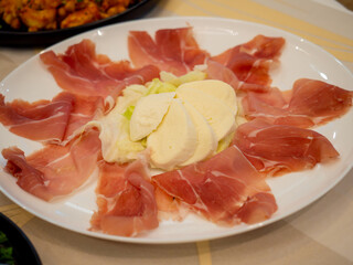 Delicious parma ham and mozzarella cheese appetizer decorating a restaurant table