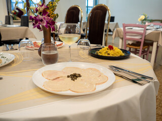 Vitello tonnato served with spaghetti and white wine at restaurant