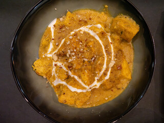 Delicious indian paneer tikka masala garnished with yogurt and nuts in a bowl