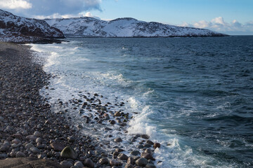View of the beach of round stones on a March day. Teriberka, Murmansk region. Russia