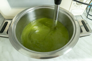 Blending broccoli cream soup in a stainless steel pot