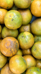 Fresh oranges with mix of green and orange hues, showcasing their natural texture and imperfections, evoke sense of harvest abundance