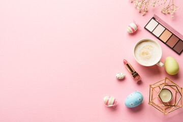 Spring flat lay background. Eyeshadow, lipstick, flower and a cup of coffee on pink.