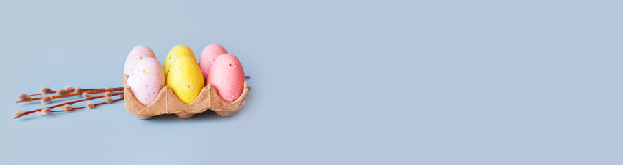 Eco basket with colorful paintedeaster eggs and willow branch on pastel light blue background. minimalistic decoration, minimal composition. Front view, place for text, banner