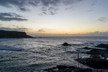 Sunset View of a Rocky Coastline with Crashing Waves Under a Dramatic Cloud-Filled Sky