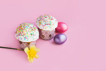 Traditional russian Easter ortodox cake with daffodil flower and colorful eggs on light pink background. Kulic, Kulich, Paska homemade bread with glaze. Spring christian holiday. Festive celebration