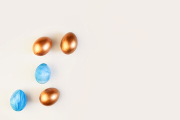 Set of Easter blue and golden color eggs isolated on white background. Stylish trendy frame composition with gold chocolate egg. Flat lay, top view, place for text. Happy egg hunt for kids concept