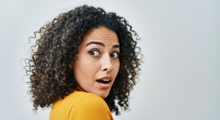 Surprised young female with curly hair looking back