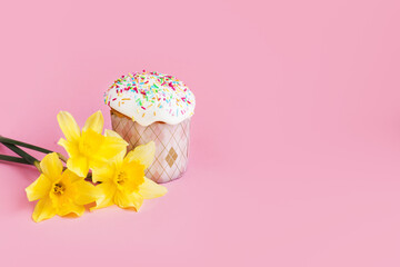 Traditional russian Easter ortodox cake with daffodil flower and colorful eggs on light pink background. Kulic, Kulich, Paska homemade bread with glaze. Spring christian holiday. Festive celebration