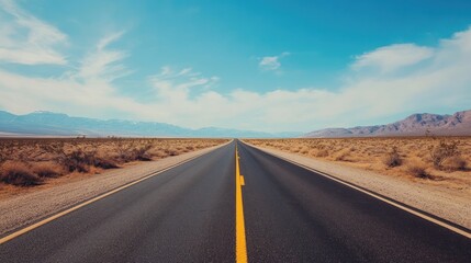 Desert highway stretching to the horizon under a clear sky with light clouds