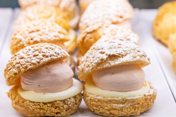A beautifully designed restaurant communal space features sleek wooden benches positioned near a floor-to-ceiling glass facade, allowing natural light to flood the area. The warm tones of the wood