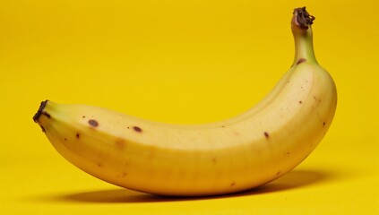 Close-up of vividly textured yellow banana peel with random dark brown spots on bright yellow backdrop