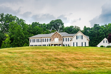 Big country house with a large green lawn in the front yard.