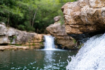 Fototapeta premium A beautiful waterfall spills gently over rugged rocks, forming a serene pool, reflecting the surrounding greenery, inviting viewers to relax and unwind in nature's embrace.