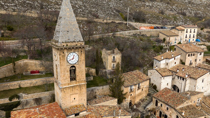 Aerial view of the clock on the bell tower of an old church in a small village. The tower is made...