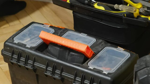 Man worker closes toolbox kit placed on floor at workshop. Specialized box for keeping necessary tools for professional repair and renovation process