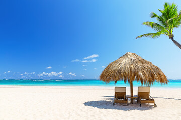 Two empty beach chairs on a summer sunny day at the beach in Punta Cana, Dominican Republic.  Amazing beach scene vacation and summer holiday concept.