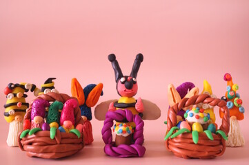 Toy little gnomes, bees and Easter baskets on a pink background.