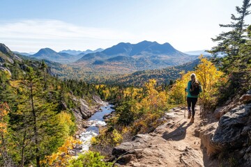 A woman standing by a river is relaxing and enjoying the beautiful fall foliage of the surrounding mountain landscape while on a hike