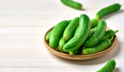 pile of Dutch holland green cucumber in wood bowl on white wooden table background with copy space