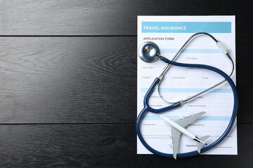Medical tourism. Travel insurance application form, stethoscope and plane model on black wooden...