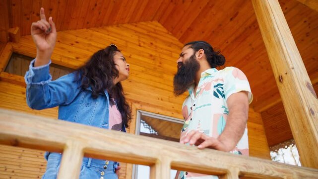 Wife points angrily at husband on timber deck outdoor