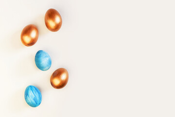 Set of Easter blue and golden color eggs isolated on white background. Stylish trendy frame composition with gold chocolate egg. Flat lay, top view, place for text. Happy egg hunt for kids concept