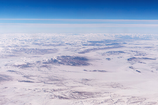 Tangla Mountain range in China, snow-capped mountain ranges like a moonscape under snow. Inner Mongolia View from an airplane window from a high altitude.