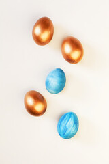 Set of Easter blue and golden color eggs isolated on white background. Stylish trendy frame composition with gold chocolate egg. Flat lay, top view, place for text. Happy egg hunt for kids concept