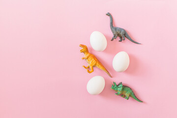 Easter egg hunt holiday composition, white eggs with dinosaur on light pastel pink backgroind. Seasonal spring kids game concept. Flat lay, minimal, trendy, top view, place for text, banner