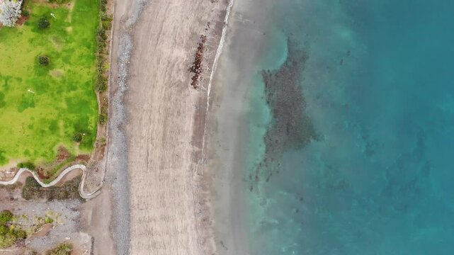 Aerial view of ocean shore, sandy beach of Costa Adeje city, Tenerife. Beautiful clear turquoise calm water on coastline, coastal tide, sand ripples. 4K drone video, dynamic birds-eye rising shot