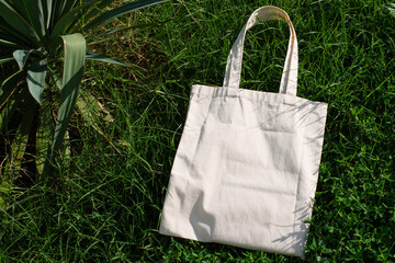 White cotton or mesh bag on green grass background. Zero waste, no plastic, eco friendly shopping,...