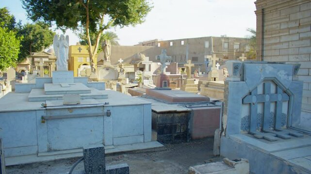 A bright cemetery filled with mausoleums, tombstones, and statues under a clear blue sky. Overview of an old Coptic cemetery in Old Cairo.