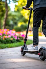 Obraz premium Young adult riding electric scooter in park on sunny day with colorful flowers.