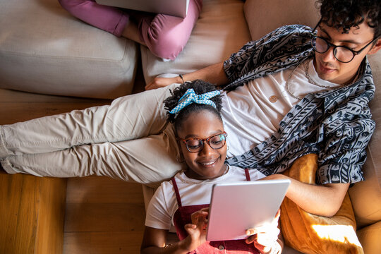 Young diverse roommates relaxing on couch using a tablet together