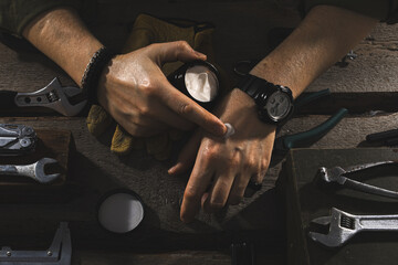 Men’s Hands Applying Cream in a Workshop Setting