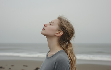 young woman on the beach. A woman standing with her eyes closed and her head tilted back,  calm atmosphere.