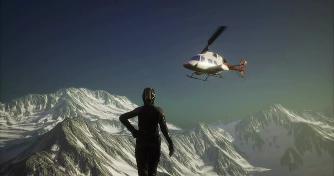 A figure stands on a mountain ridge, gazing up as a helicopter flies overhead against the backdrop of towering snow capped peaks during daylight.