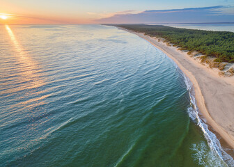A stunning Curonian Spit beach at sunrise, with turquoise waters, soft sand, and gentle waves lapping the shore, captured from above.