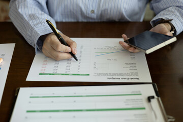 the businessman is sitting at a desk with a calculator and a stack of papers. She is looking at the...