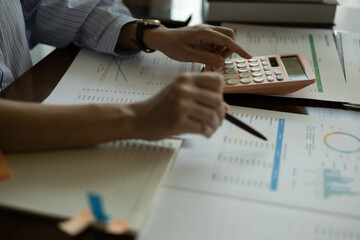 the businessman is sitting at a desk with a calculator and a stack of papers. She is looking at the...