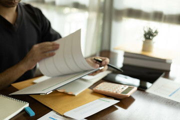 the businessman is sitting at a desk with a calculator and a stack of papers. She is looking at the...
