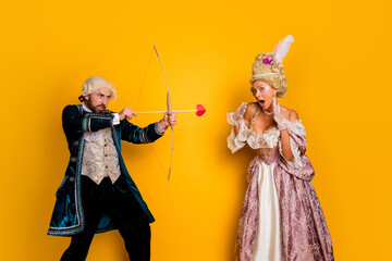 Vintage-era costumed couple in themed attire posing against a yellow background for a carnival party