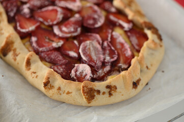 Freshly baked strawberry galette on parchment paper, capturing the essence of summer desserts in a cozy kitchen
