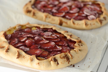 Freshly baked fruit galettes resting on parchment paper, showcasing a vibrant assortment of strawberries and rich golden crust
