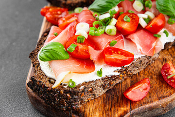Bruschetta ham, tomato, greens dish fresh delicious gourmet food background on the table rustic food top view copy space