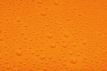 Orange plastic with water drops macro photo as background.