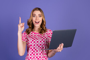 Excited young woman holding a laptop with a lively expression in a stylish outfit