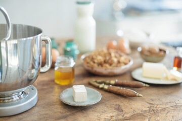 In a rustic kitchen, warm light highlights rising dough mixed with walnuts. A wooden table displays fresh produce and wholesome ingredients for homemade bread